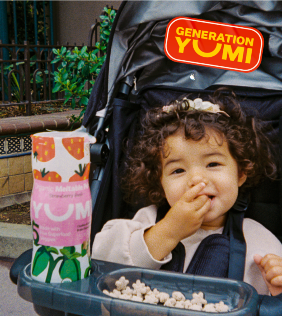 Child eating YUMI pops in pram. 